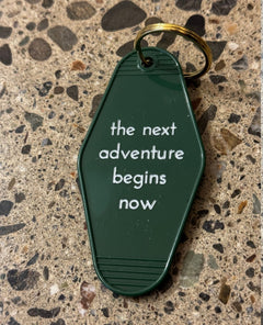 The Next Adventure Begins Now Keychain - miamidrugpossession